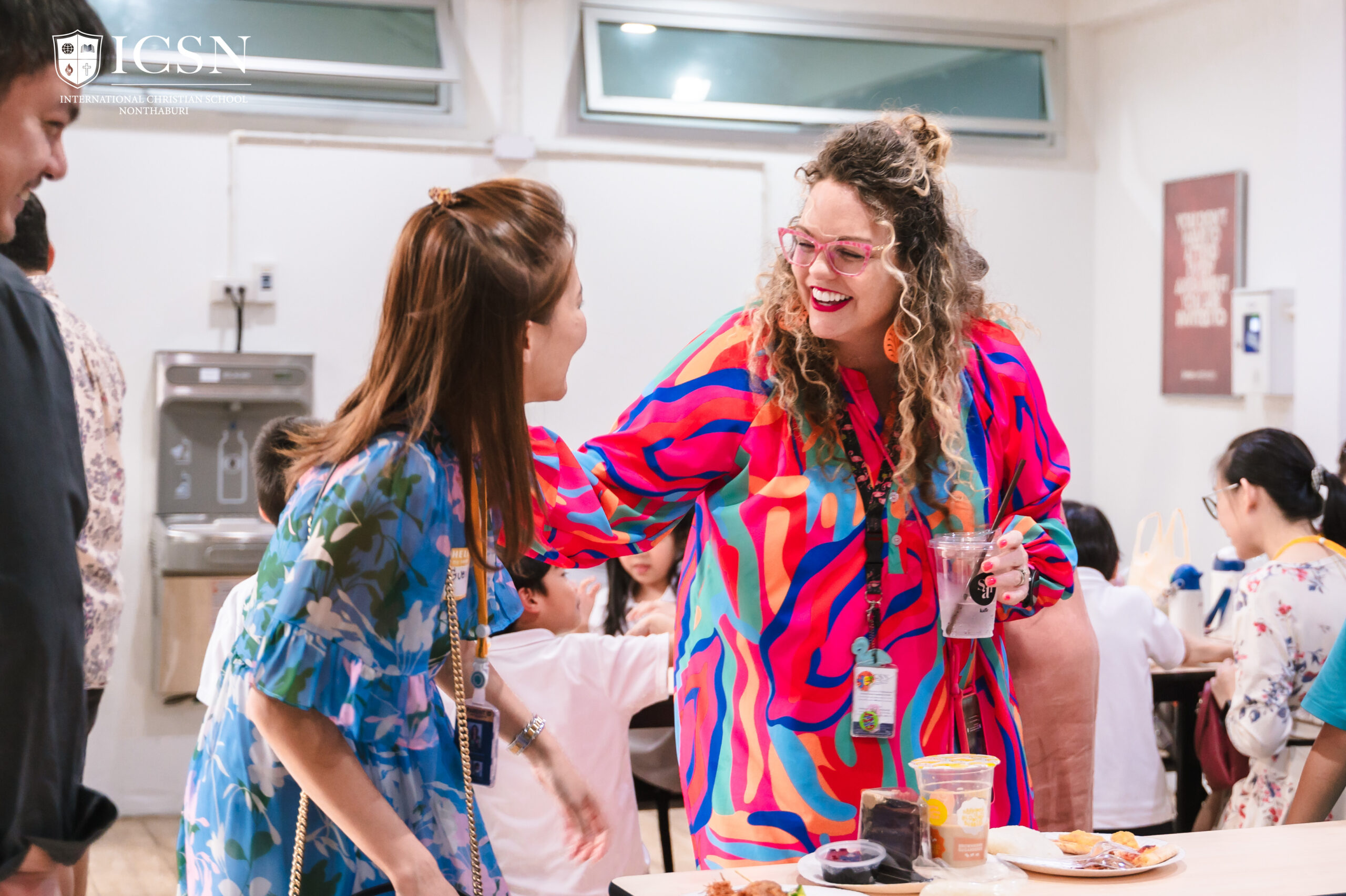 A parent and teacher laughing at a parent-teacher’s potluck