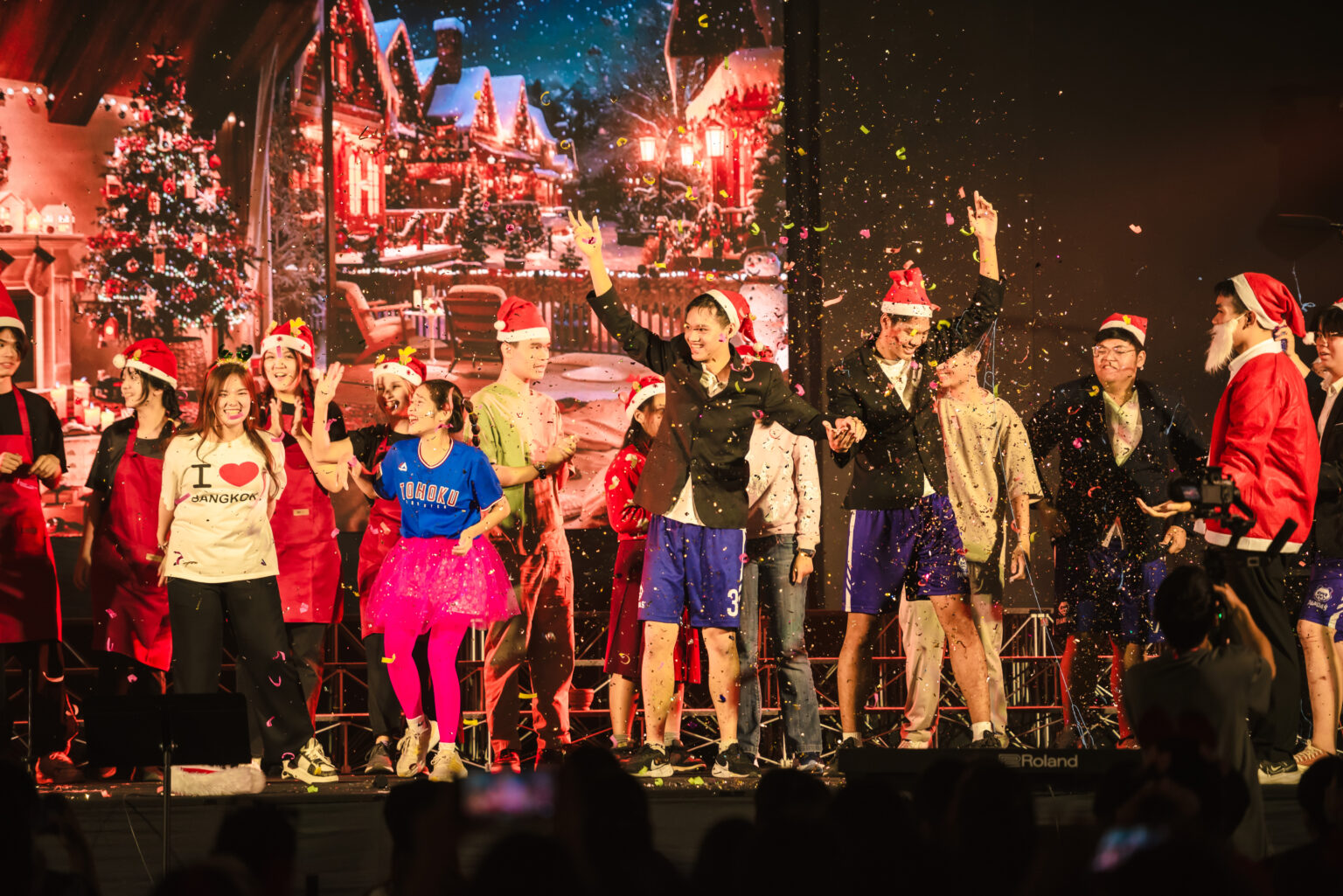 Students in costumes and Christmas hats performing a Christmas presentation with confetti falling from above