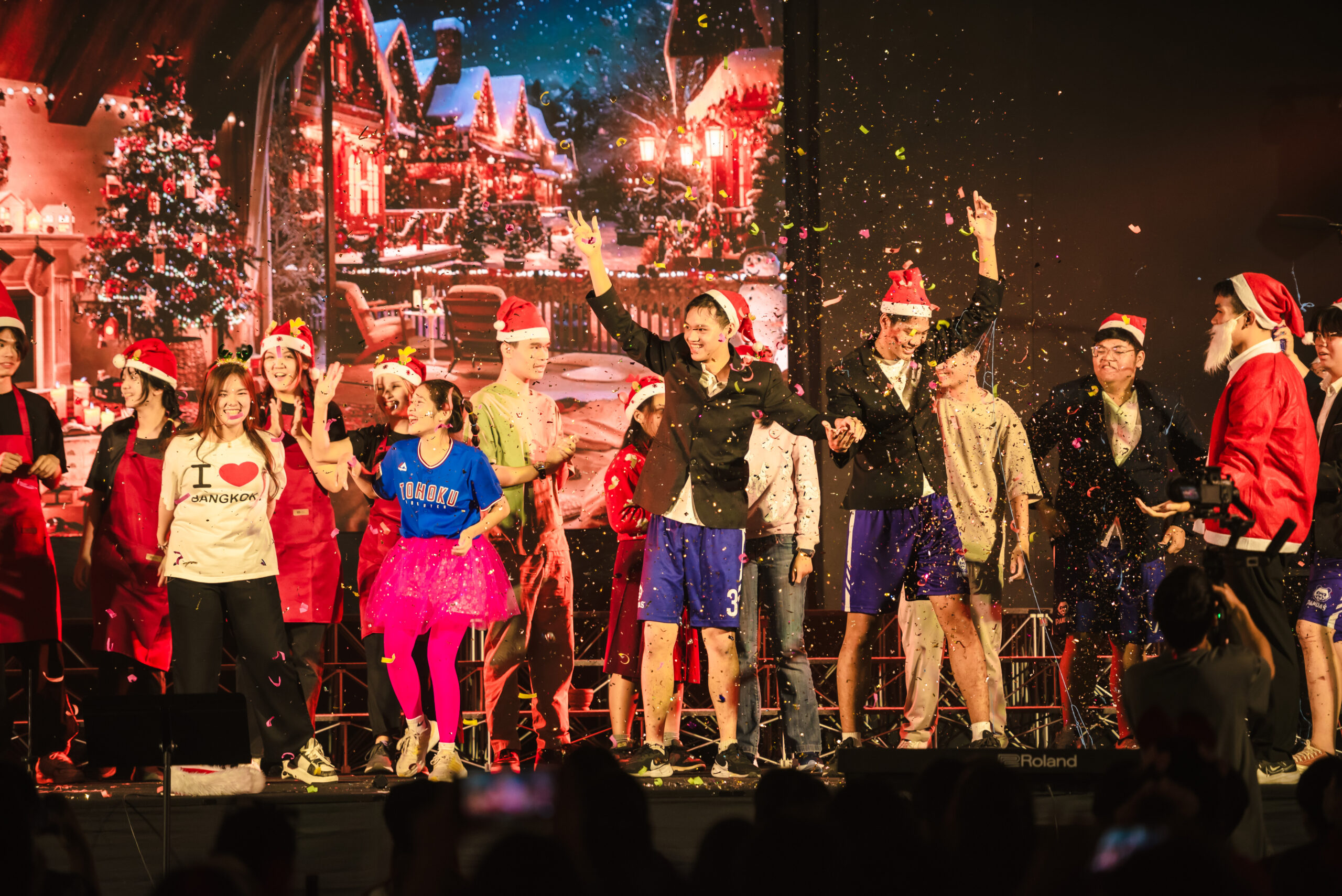 Students in costumes and Christmas hats performing a Christmas presentation with confetti falling from above