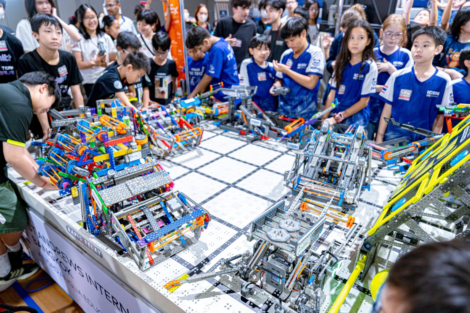 Robotics competitors surrounding a table filled with robots