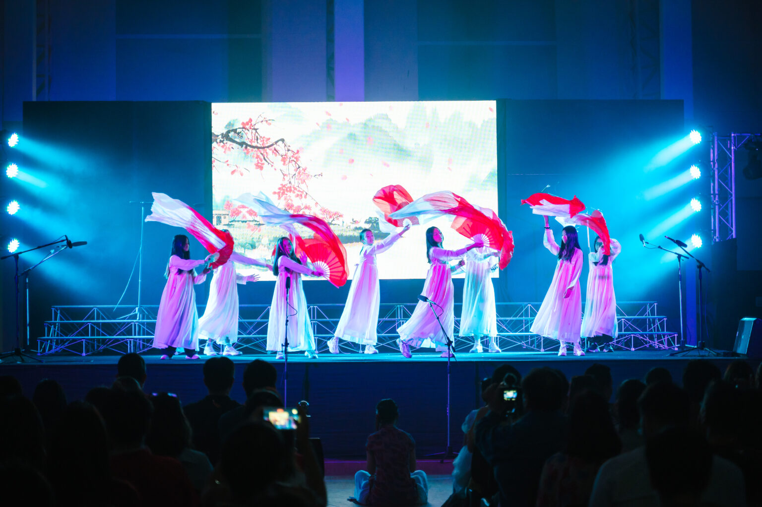 Students performing an interpretative dance on stage with fans and cloth