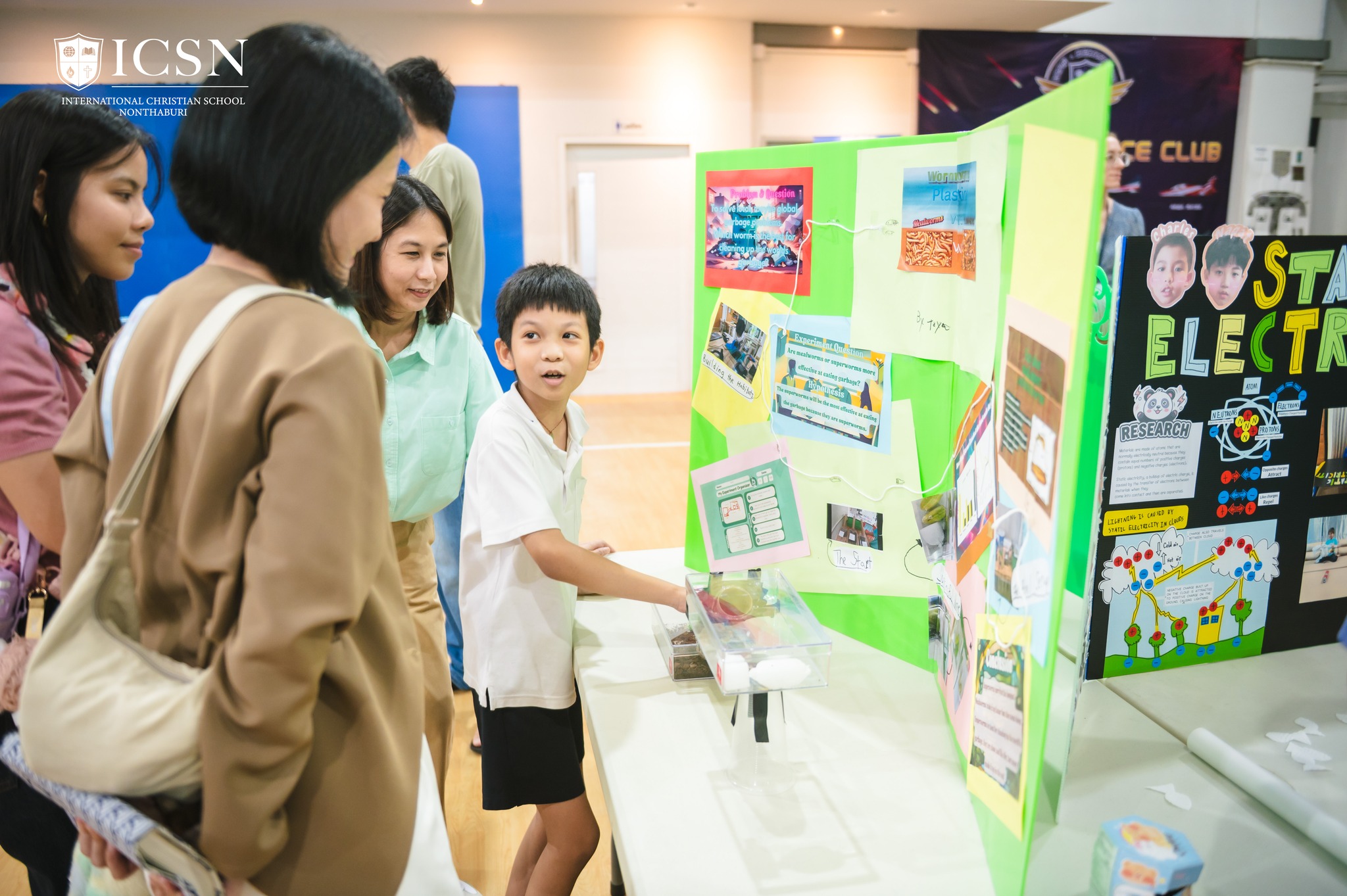 a student presenting his science fair project to parents and visitors