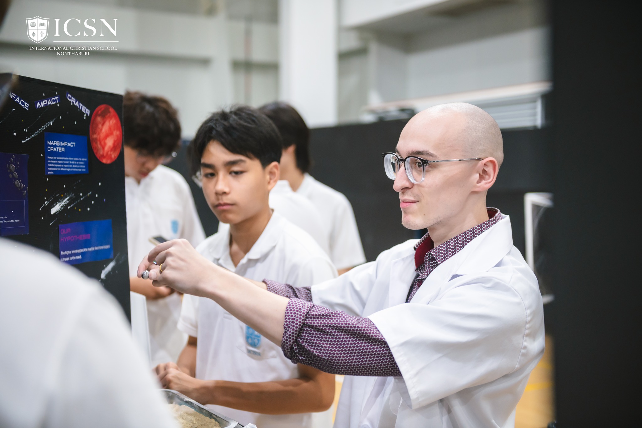 Science Fair judge in a lab coat interviewing students about their project