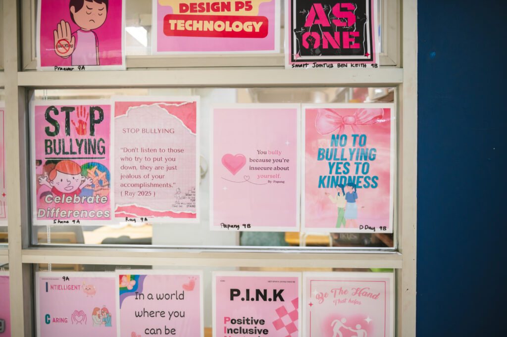 Pink themed posters about anti bullying posted on a glass wall