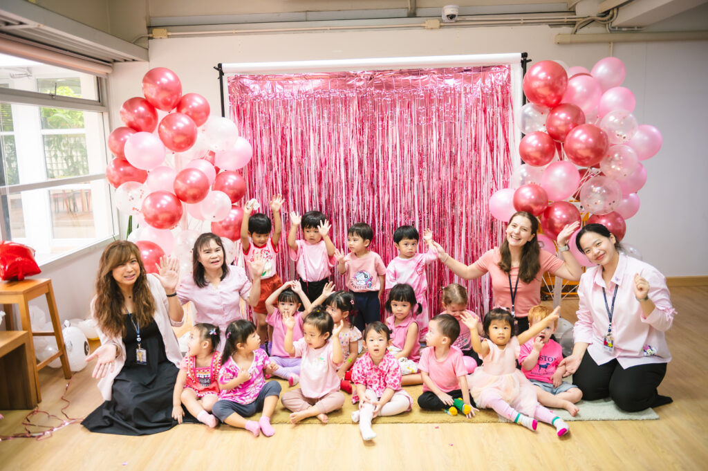 Kids and teachers wearing pink at a pink and red decorated photobooth