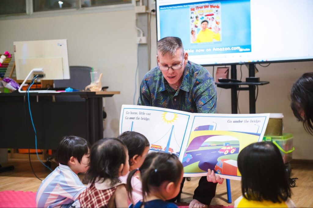 A teacher flipping a giant book for his kindergarten students.