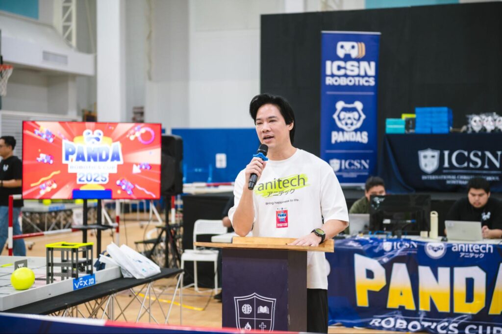 An inspirational speaker standing on a podium sharing insights at a robotics competition