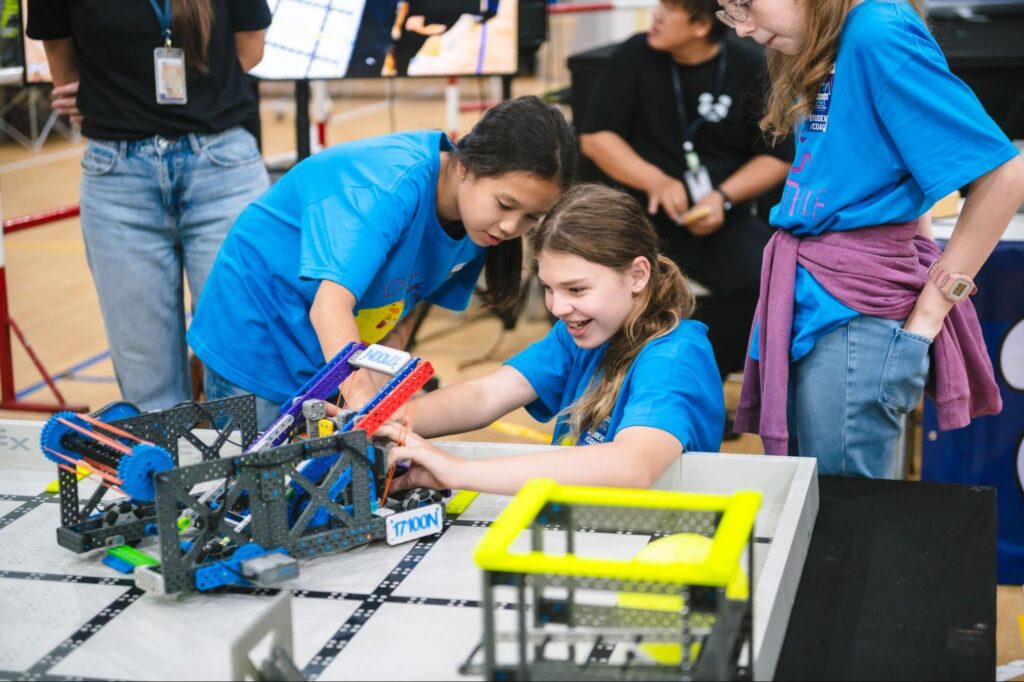 Two students preparing their robots at a robotics competition