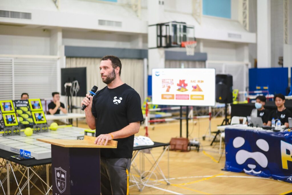 a speaker on a podium holding a microphone in a robotics competition
