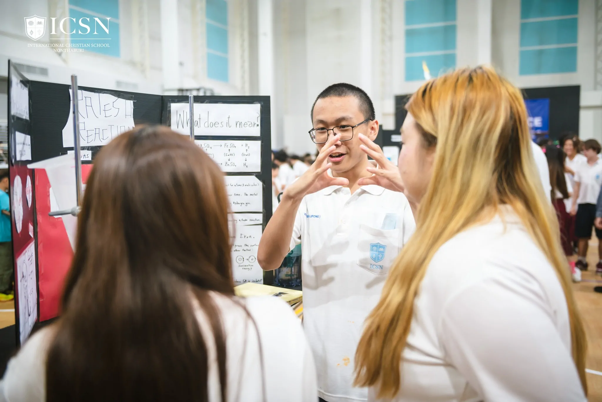 A student presenting his science fair project to a guest.